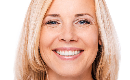 Portrait of happy mature woman looking at camera and smiling while standing against white background